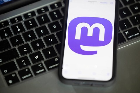 Logo of Mastodon, a new social networking service pictured here on a mobile phone above a keyboard