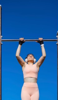 Young girl doing calisthenics exercise on bars outdoors. pull-up exercise