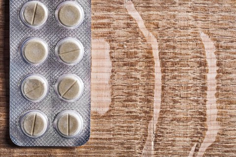 Blister pack with pills on vintage wooden board with organised copyspace medical concept