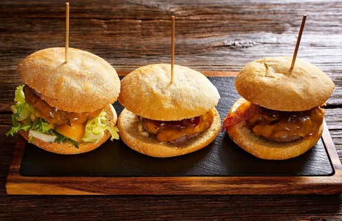 Burger in a row on a slate board and wood table
