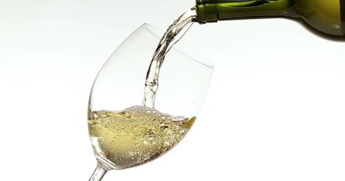 White Wine being poured into Glass, against White Background