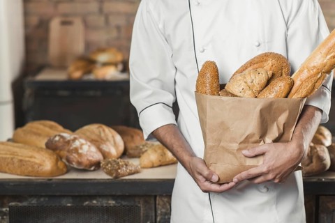 Mid section male baker holding paper bag with breads. Resolution and high quality beautiful photo