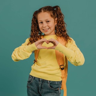 School girl with yellow shirt making heart shape