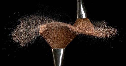 Make-up Brush spreading blush powder on black background
