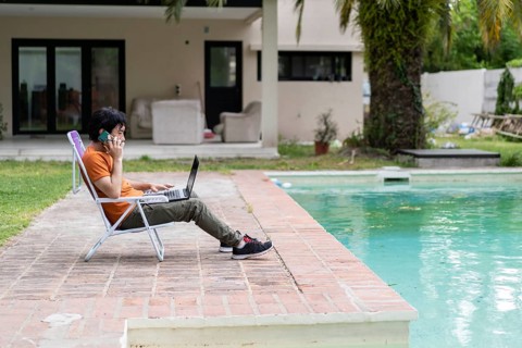 Latin man working on his laptop in the pool