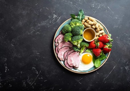 Ketogenic low carbs diet, top view, space for text. Plate on stone black background with keto