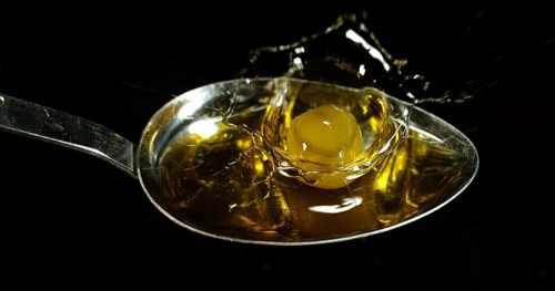 Green Olive, Olea europaea, Falling in a Spoon against Black Background
