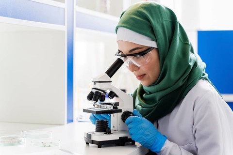 Side view female scientist with hijab microscope