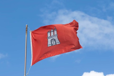 Red flag with the coat of arms of Hamburg against a blue sky in Hamburg, Germany, Europe