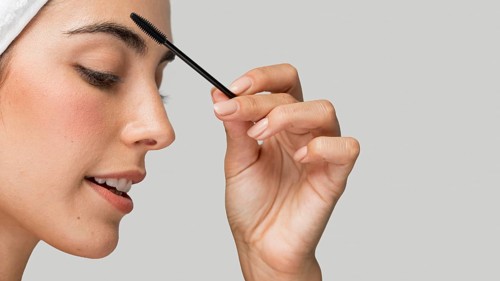 Sideways woman applying mascara her lashes