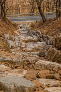 Drainage ditch constructed of large boulders on side of mountain on early spring afternoon in South