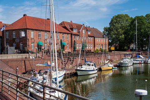 Sailing yachts on the promenade with brick houses and a terrace in sunny weather and blue sky,