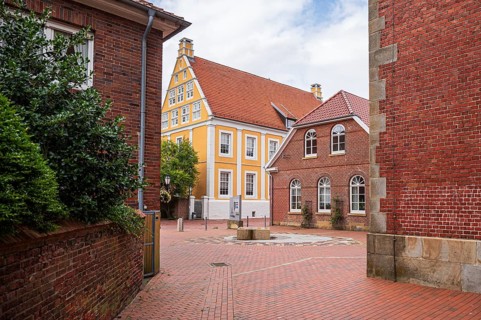 Idyllic alley with orange building and cobblestones between brick buildings, Lingen, Emsland, Lower