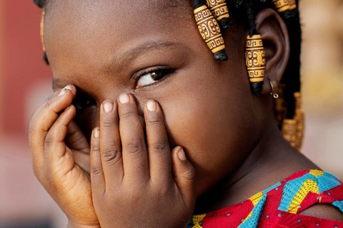 Close up african girl covering her face
