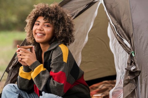 Smiley woman camping outdoors with tent