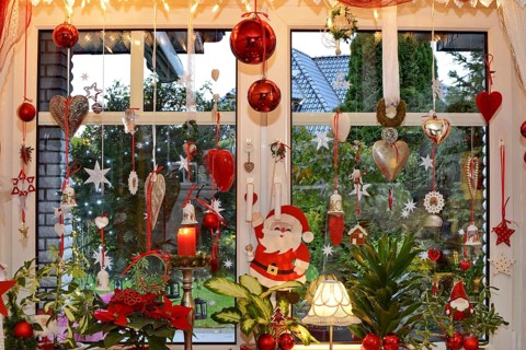Christmas decorated window with fairy lights, Christmas balls, hearts, stars, bells, candle, Santa