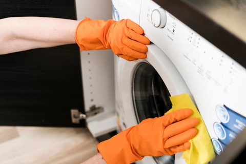 High angle woman cleaning washing machine. High resolution photo