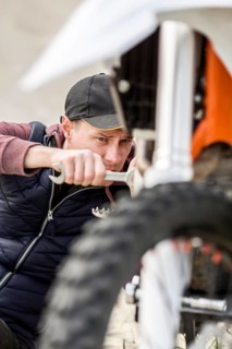 Portrait man trying fix motorbike