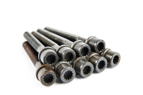 A set of new cylinder head bolts in oil on a white isolated background are shot in perspective at a