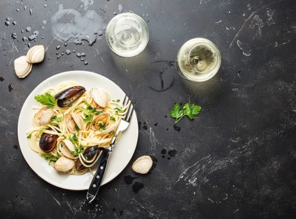 Spaghetti vongole, Italian seafood pasta with clams and mussels, in plate with herbs and two