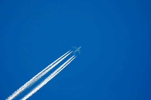 Four-engine jet with condensation trails in the blue sky