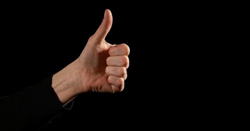 Hand of Woman making Sign against Black Background