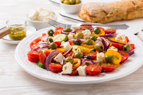 Greek salad of fresh cucumber, tomato, sweet pepper, lettuce, red onion, feta cheese and olives