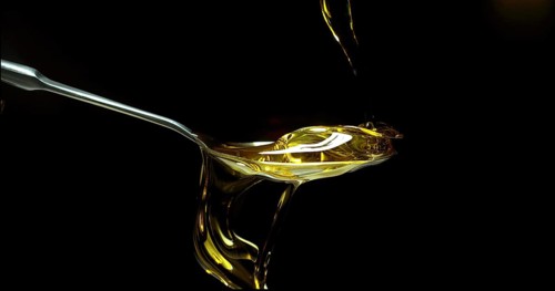 Olive Oil, Falling in a Spoon against Black Background