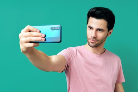 Portrait of handsome man taking selfie over blue background