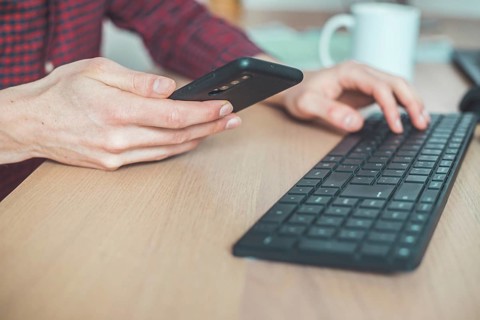 Young man is holding mobile phone in his hands, indoor at home office