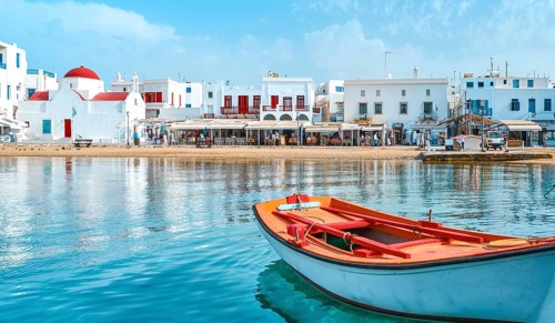 Beautiful summer day sunshine on Greek island. Fishing boats moored at jetty. Whitewashed houses by
