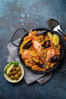 Classic dish of Spain, seafood paella in traditional pan on rustic blue concrete background top