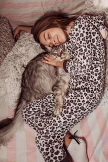 Girl pajamas hugging her cat laying bed