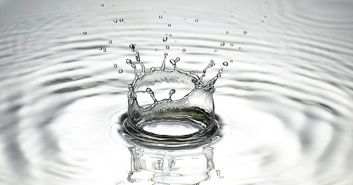 Drop of Water falling into Water against Grey background