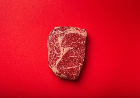 Raw fresh uncooked meat beef prime cut steak Ribeye on clean red background from above, beefsteak