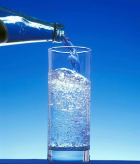 Sparkling Water being Poured in a Glass against Blue Background
