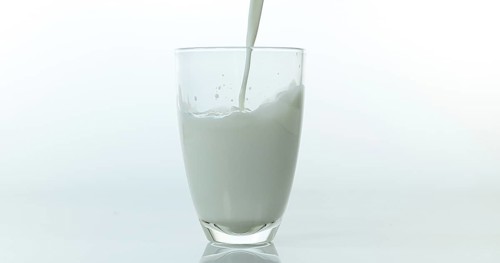 Milk being poured into Glass against White Background