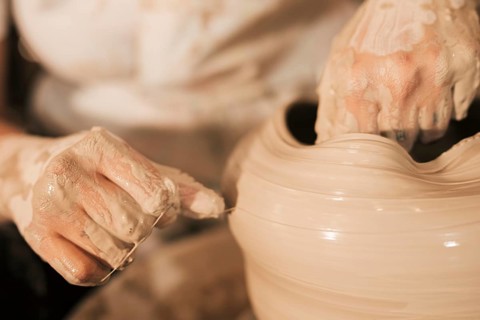 Potter aligns wet clay pot with thread potter s wheel
