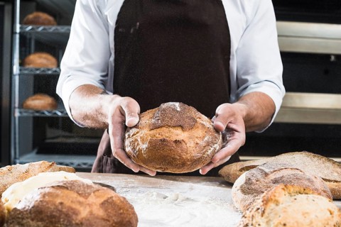 Close up male baker showing loaf bread