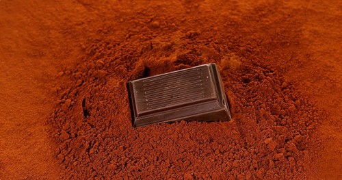 Black Chocolate Tablet falling on Black Chocolate Powder