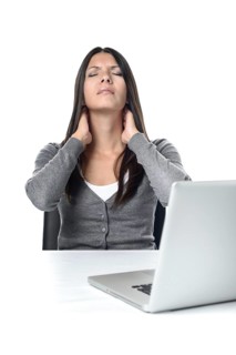 Attractive young businesswoman sitting at her laptop rubbing her neck with a grimace to relieve