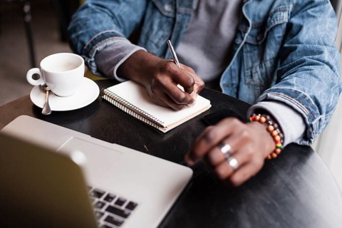 Unrecognisable man writing notebook