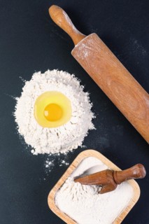 Rolling pin and white flour on a dark background. Top view