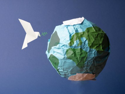 Abstract globe made of crumpled paper with origami peace dove, global freedom and peace concept