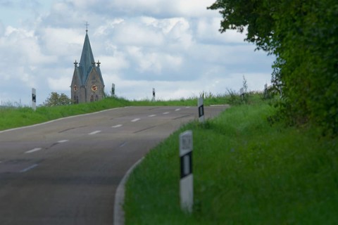 Country road with a view of the village church in Bibersfeld, Swabian-Franconian Forest nature park
