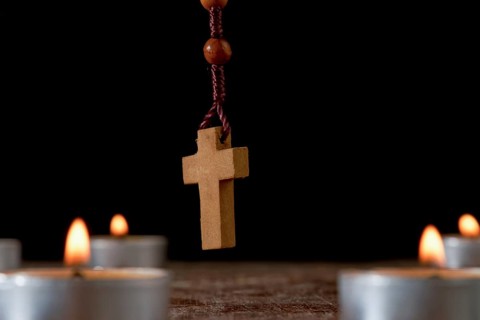 Circle of lighted candles with a wooden Rosary praying beads in the center and a smoldering incense