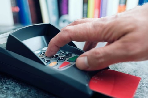 close-up of person entering PIN number on POS credit card payment terminal