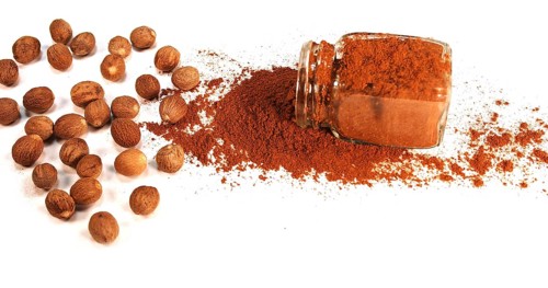 Nutmeg, myristica fragans, Nut falling on Nutmeg Powder against White Background