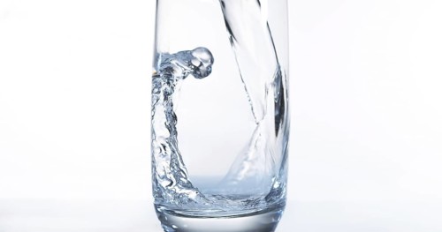 Water being poured into Glass against White Background