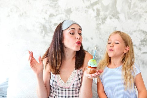 Birthday portrait of the mother and her daughter with cupcake in the morning